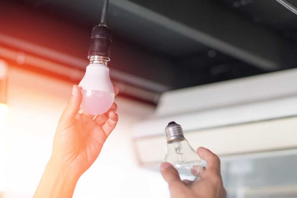 man changing compact-fluorescent (CFL) bulbs with new LED light bulb