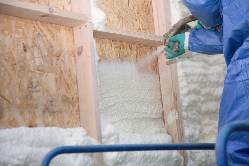 A man applies an insulating foam to the wall of the house