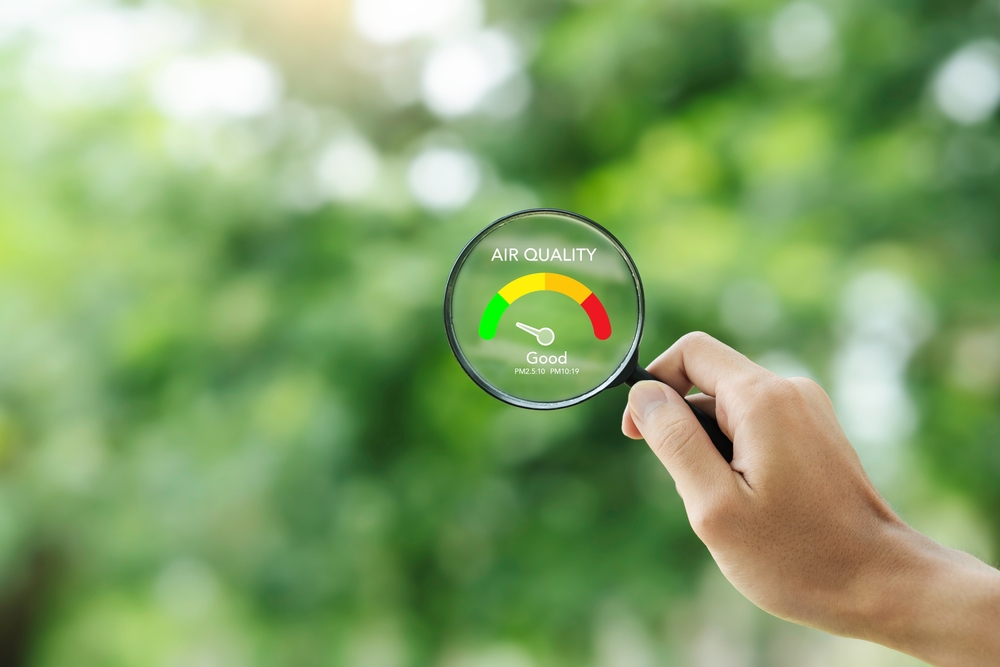 hand holding a magnifying glass to check the good air quality and clean outdoor air