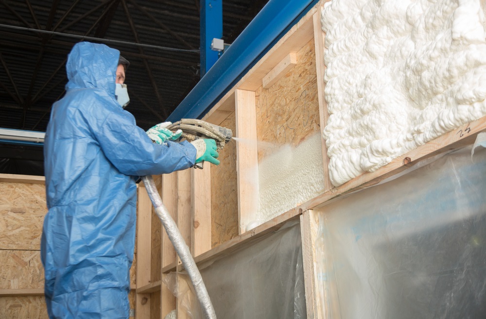 The worker insulates the walls of the building with foam for sound insulation and heat