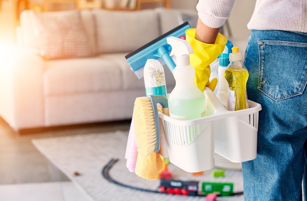 Cleaning, hand and basket of cleaning supplies for family home hygiene with a brush, bottles and gloves