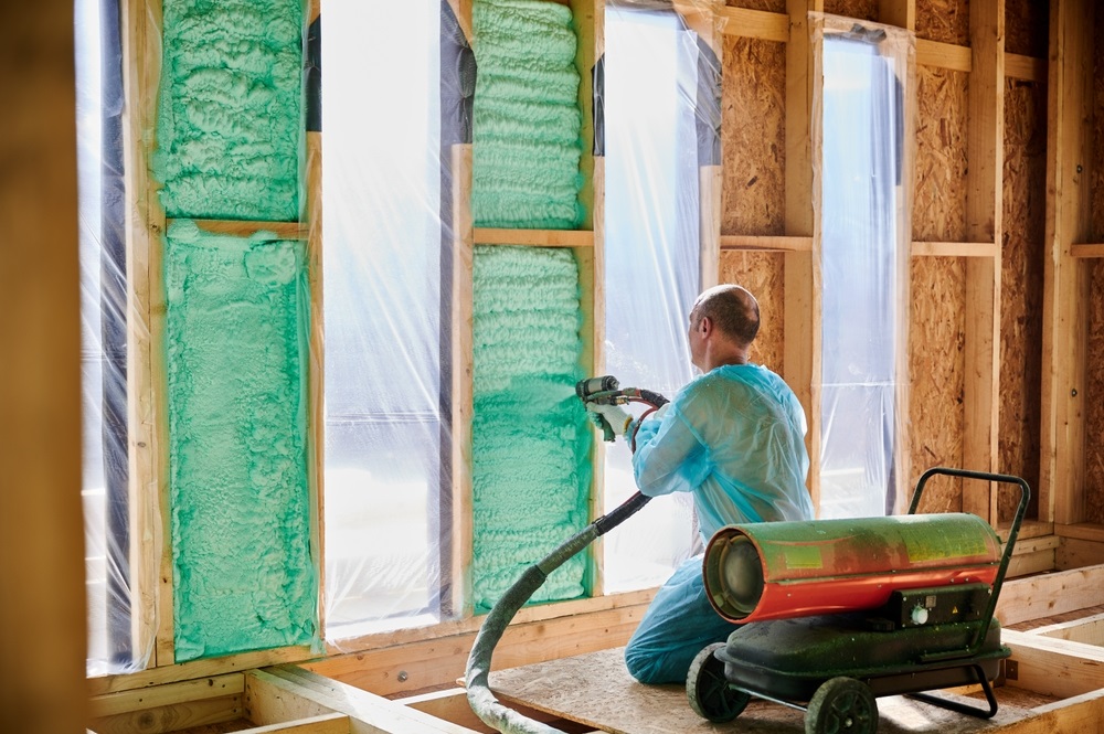 Man worker spraying polyurethane foam inside a newly built homea