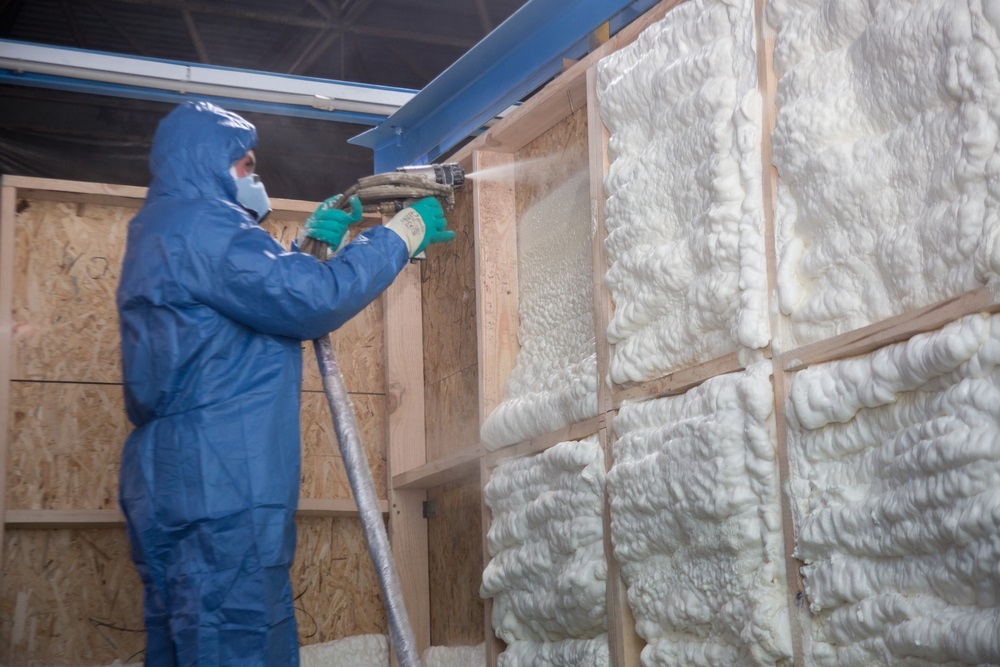 The worker insulates the walls of the house with foam for sound insulation and heat