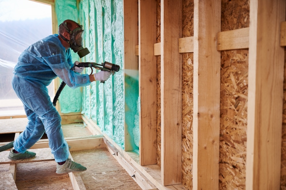 Male builder insulating wooden frame hous