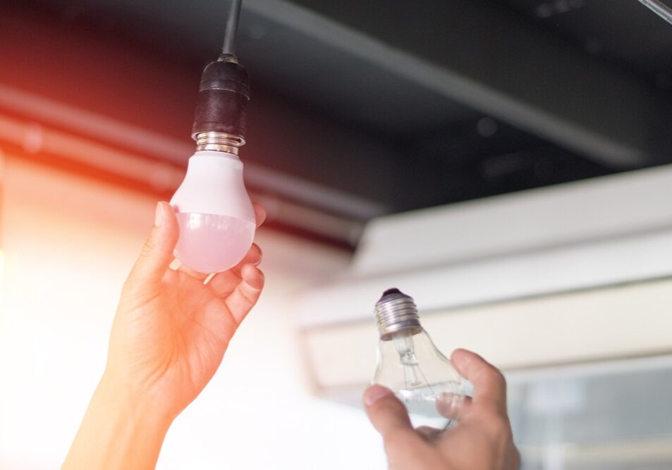 man changing compact-fluorescent (CFL) bulbs with new LED light bulb man changing compact-fluorescent (CFL) bulbs with new LED light bulb