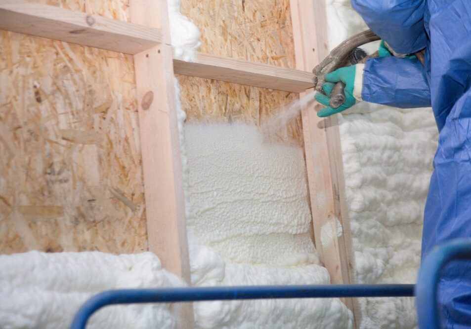 A man applies an insulating foam to the wall of the house A man applies an insulating foam to the wall of the house