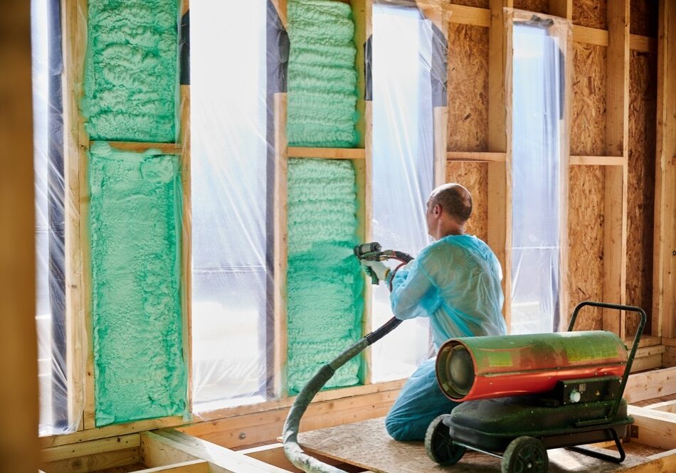 Man worker spraying polyurethane foam inside Man worker spraying polyurethane foam inside a newly built homea